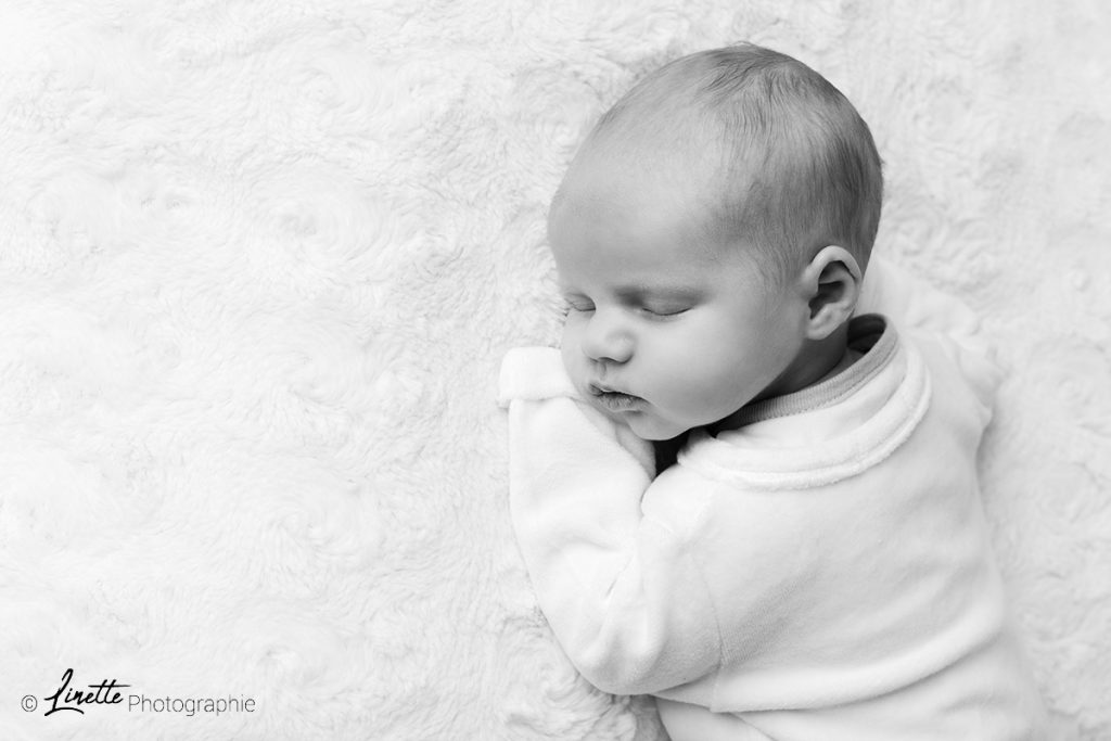 Photo de naissance E. par Linette Photographie. Photographie en noir et blanc d'un nouveau né endormi.