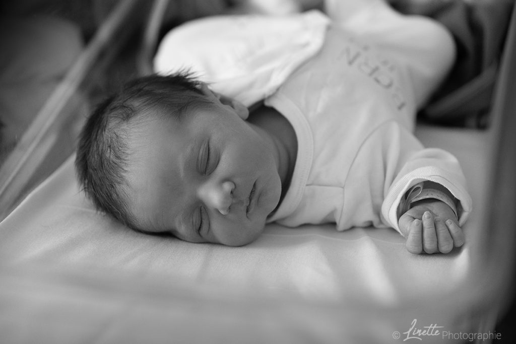 Petit garçon dans son berceau à la maternité. Photo prise lors d'une séance naissance en reportage.