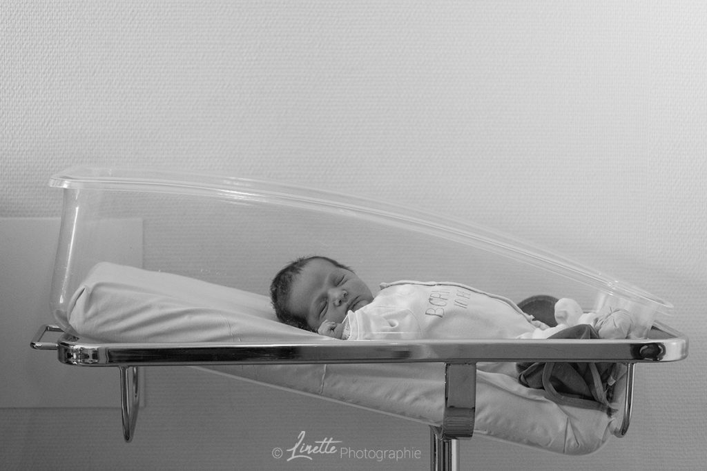 Petit garçon dans son berceau à la maternité. Photo prise lors d'une séance naissance en reportage.